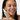 Smiling woman with glowing, even-toned skin and freckles holding Active Drip Kojic Drip serum
